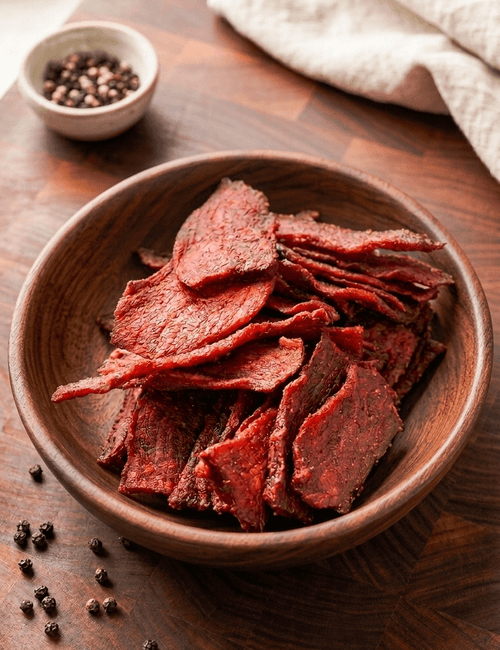 Slices of BBQ Beef Jerky piled in a round wooden bowl