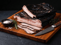Sliced Black Forest Bacon arranged on a wooden cutting board