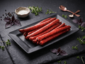 Several Buffalo Pepperoni Sticks arranged on a black rectangular plate