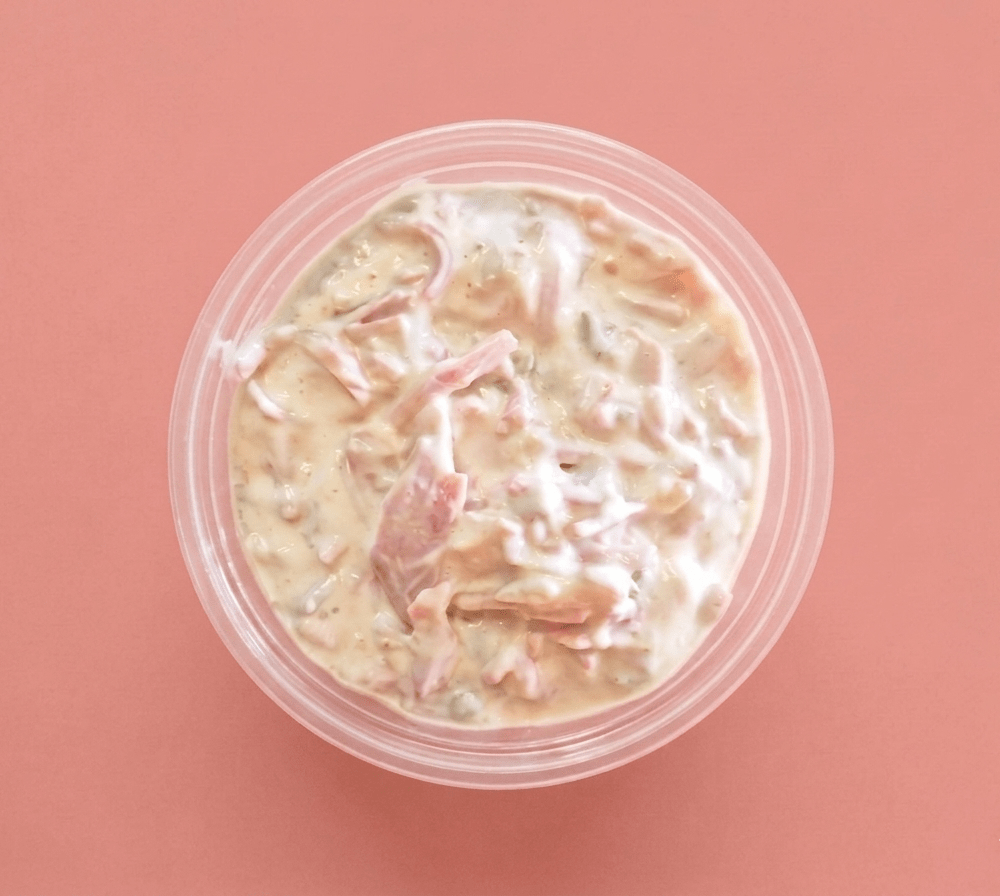 A top-down view of Coldcut Salad in a clear round plastic container