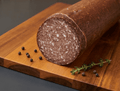 A cut loaf of German Salami resting on a wooden cutting board