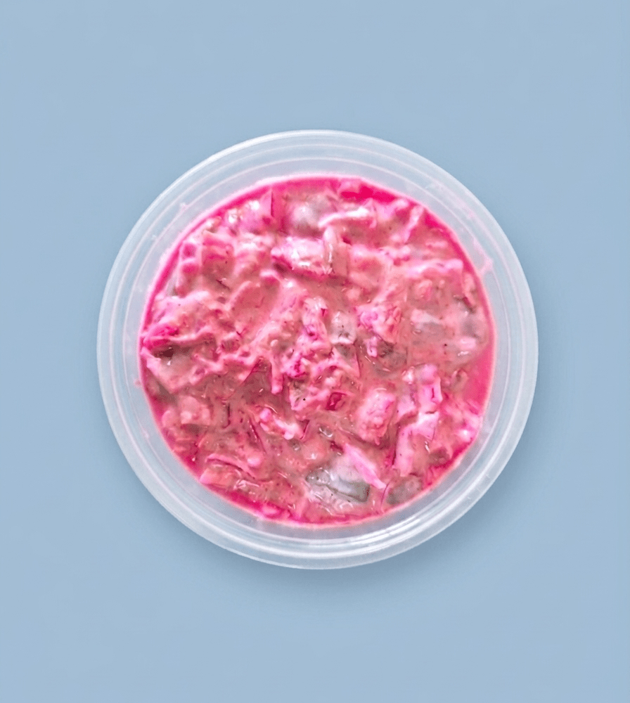 A round, clear plastic tub filled with Herring Salad
