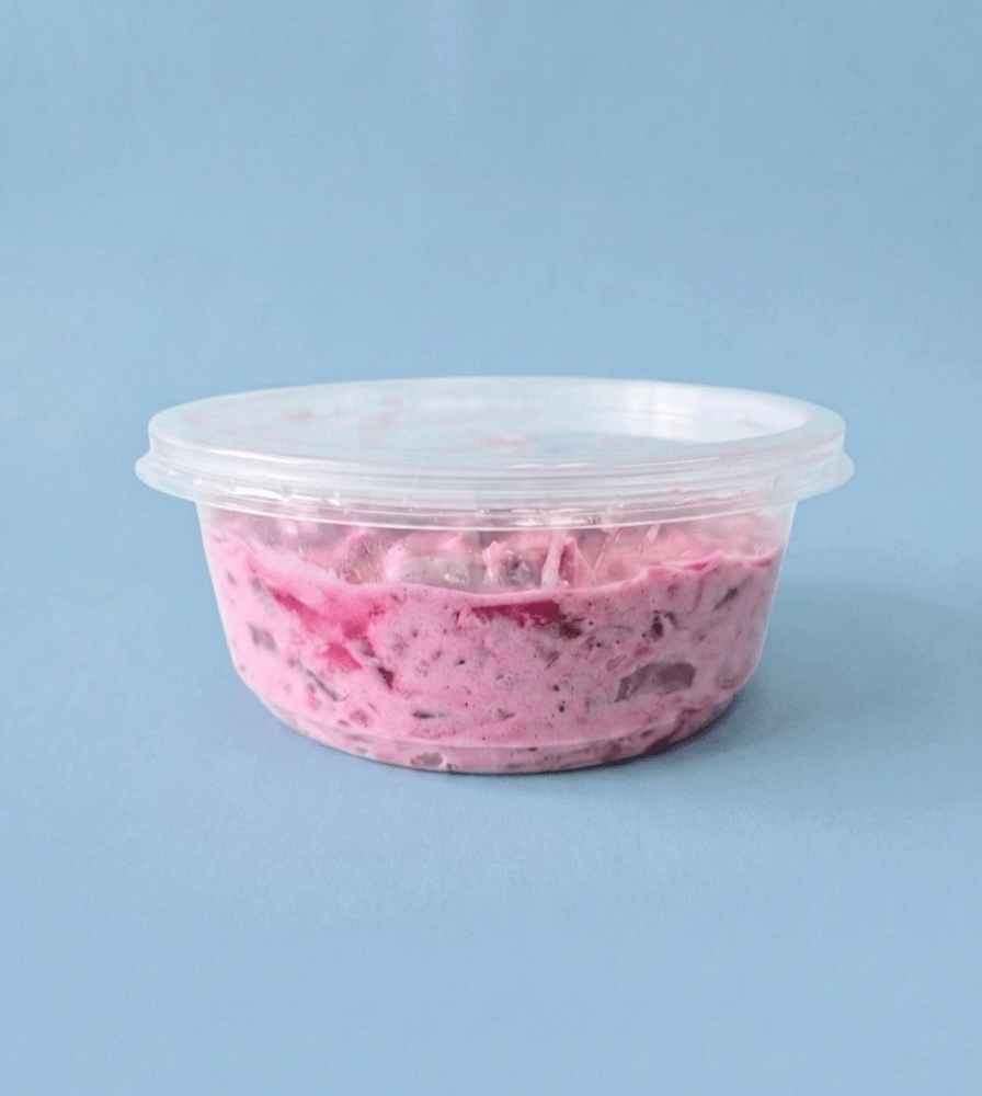 A round clear plastic tub with matching lid containing a Herring Salad