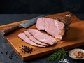 A sliced piece of Pastrami on a wooden cutting board