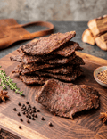 Stacked slices of Pepper Beef Jerky arranged on a wooden cutting board