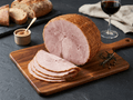A sliced Rosemary Ham on a wooden cutting board